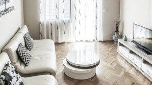 A modern living room with a sofa, a coffee table, a TV, and a large window with sheer curtains. - Awesome home in Polaca (Polaca)