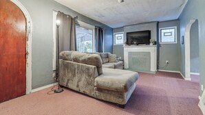 Ein Wohnzimmer mit einem großen Ecksofa, einem Kamin und einem Fernseher.