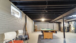 Ein Zimmer mit Billardtisch, Stühlen und einer Leiter.