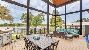 A covered outdoor deck with a grill, dining table, and seating area. - Private Dock & Yard! Modern Getaway in Mabank (Mabank)