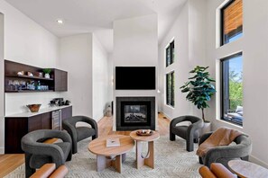 A modern living room with a fireplace, seating area, and a bar with shelves. - Luxury Mountain Estate, Sleeps 12, Theater, Games & Hot Tub (Campton)