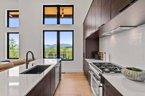 A modern kitchen with a central island, large windows, and a view of the outdoors. - Luxury Mountain Estate, Sleeps 12, Theater, Games & Hot Tub (Campton)