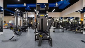 Een sportschool met diverse fitnessapparaten, waaronder krachtapparaten en gewichten.