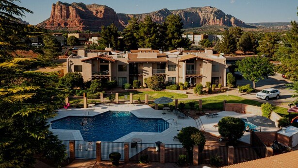Un hôtel doté d’une piscine, entouré d’arbres et avec des montagnes en toile de fond.