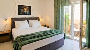Habitación de hotel con cama, un cuadro, una mesita de noche, un vaso de agua y vistas al exterior.