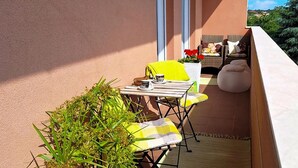 A balcony with a table and chairs, a potted plant, and a wicker sofa with cushions. - Gorgeous apartment in Medulin (Medulin)
