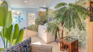 A room with a large fan, a washing machine, a glass table, and a mural of palm trees. - Mediterranean-Style Cottage Near Paso Robles  Slp4 (Atascadero)