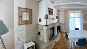 A room with a stone fireplace, a dining table with chairs, a large mirror, and a dreamcatcher on the wall. - Family home near the beach, enclosed garden, 4 bedrooms, sleeps 10 (Loctudy)