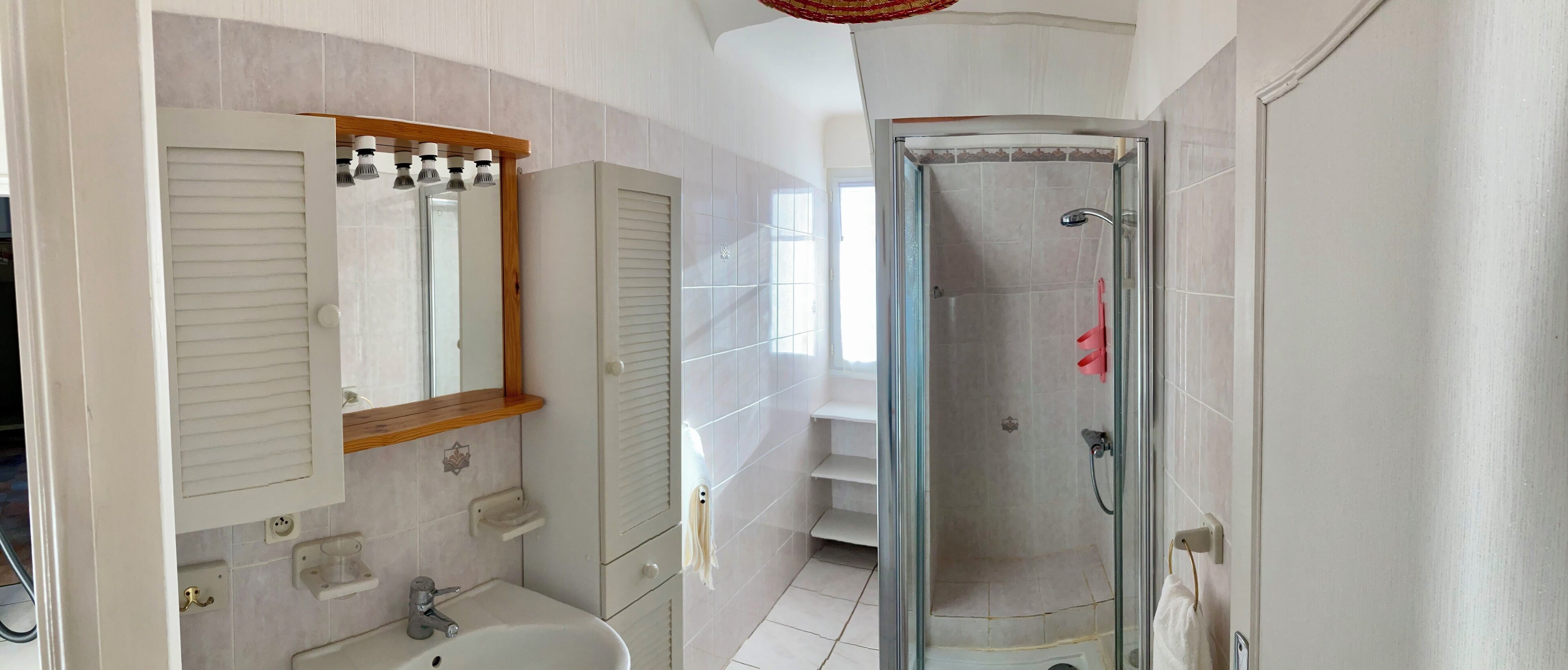 A bathroom with a glass-enclosed shower, a sink, a mirror, and a towel rack.
