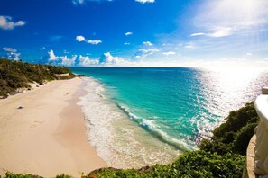 A beach with clear turquoise water, a sandy shore, and a view of the ocean.