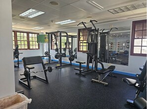 A gym with various exercise equipment, large windows, and a mirror.