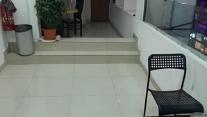 A clean, tiled floor with a black chair and table, a potted plant, and a fire extinguisher. - NOVA HOTEL BUKIT BINTANG (Kuala Lumpur)