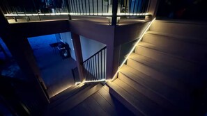 Eine moderne Treppe mit Holzstufen und Metallgeländern, die zu einem Balkon mit Blick auf ein abgestelltes Motorrad führt.