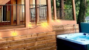 Eine Holzterrasse mit Whirlpool, Metallgeländern und Lichterketten.