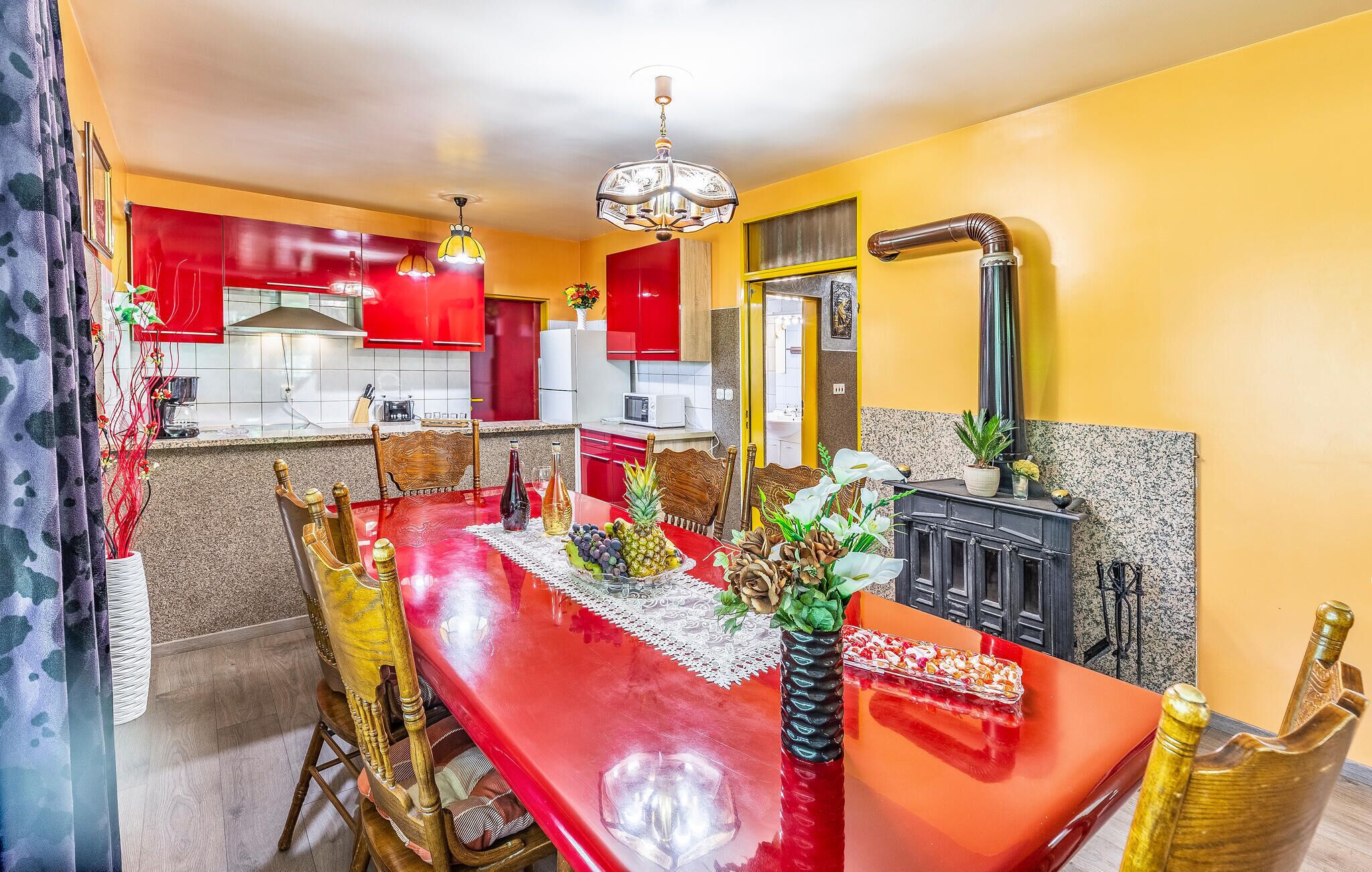 Un coin repas avec une table rouge, des chaises et un élément décoratif au centre.