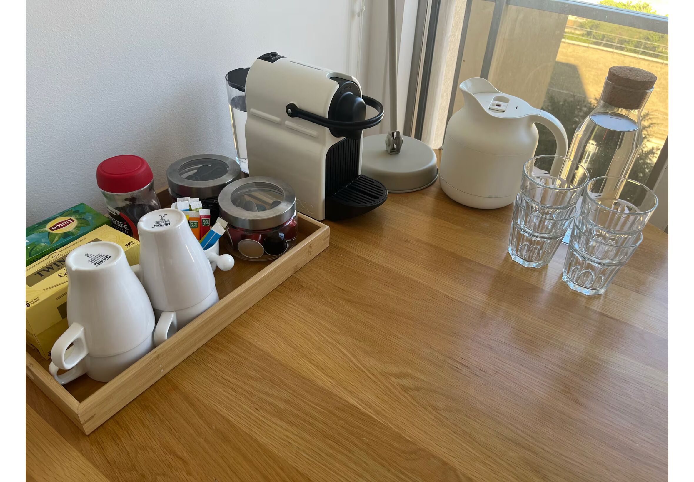 Un coin cuisine équipé d’une machine à café, d’une bouilloire et d’un plateau avec des tasses et des pots.