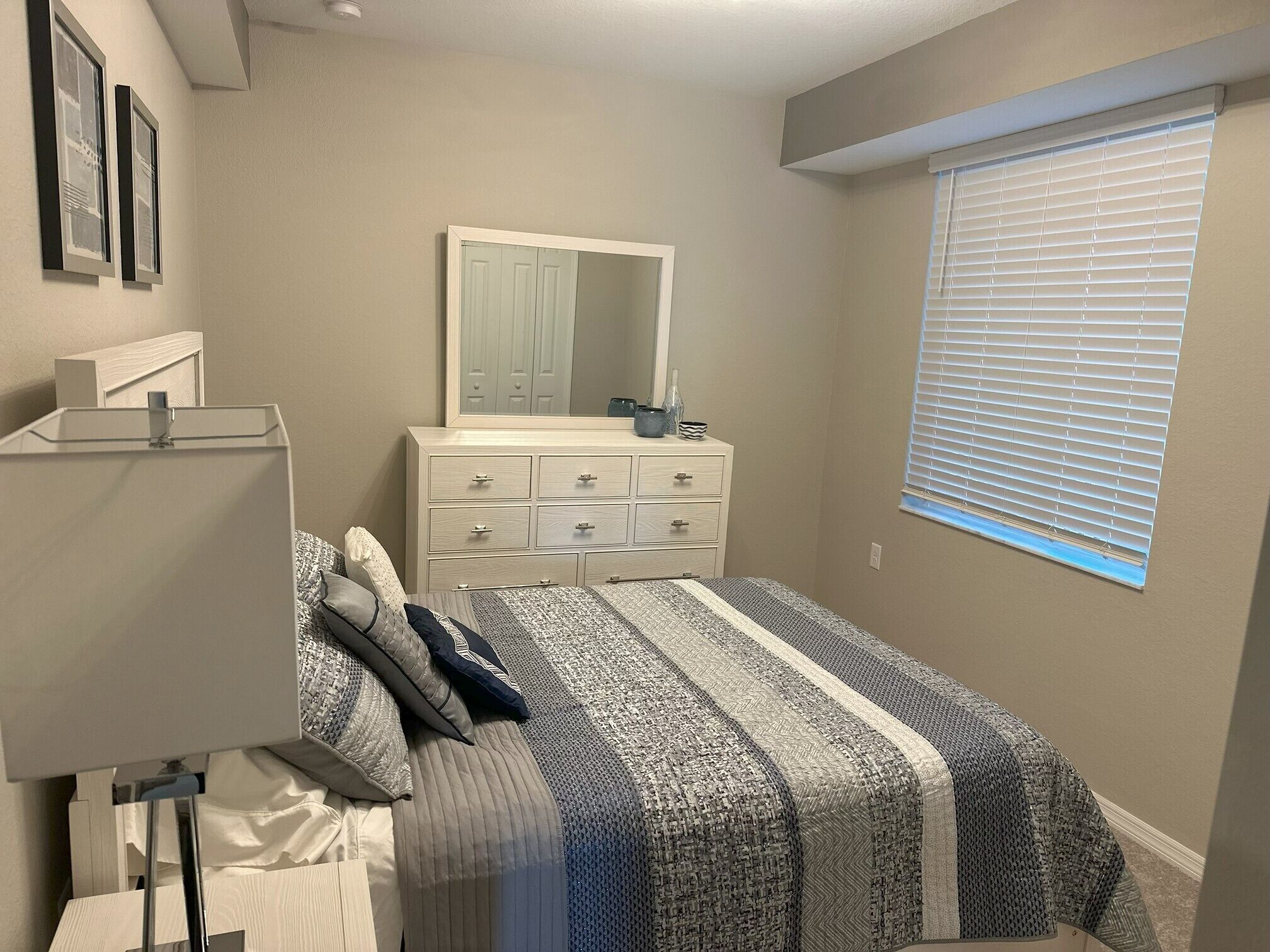 Une chambre à coucher avec un lit, une commode, un miroir et une fenêtre.