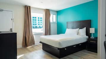 Un dormitorio con una cama, una mesita de noche, un escritorio y una ventana con cortinas.
