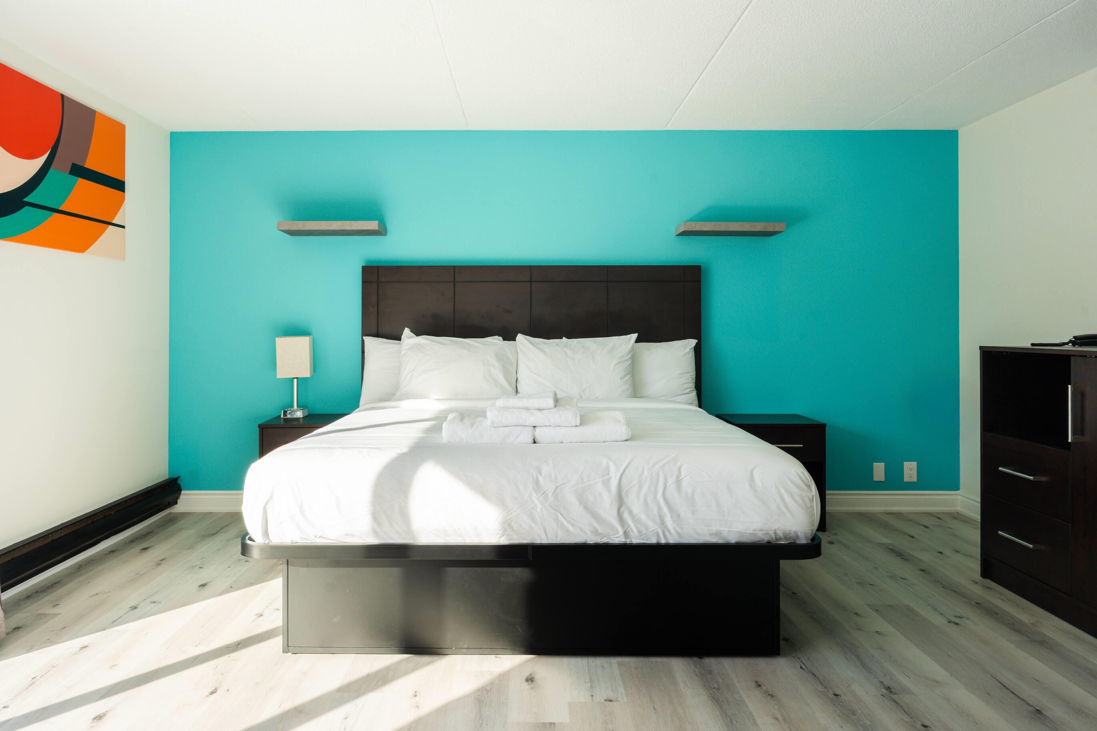 A modern bedroom with a bed, nightstands, and a dresser.