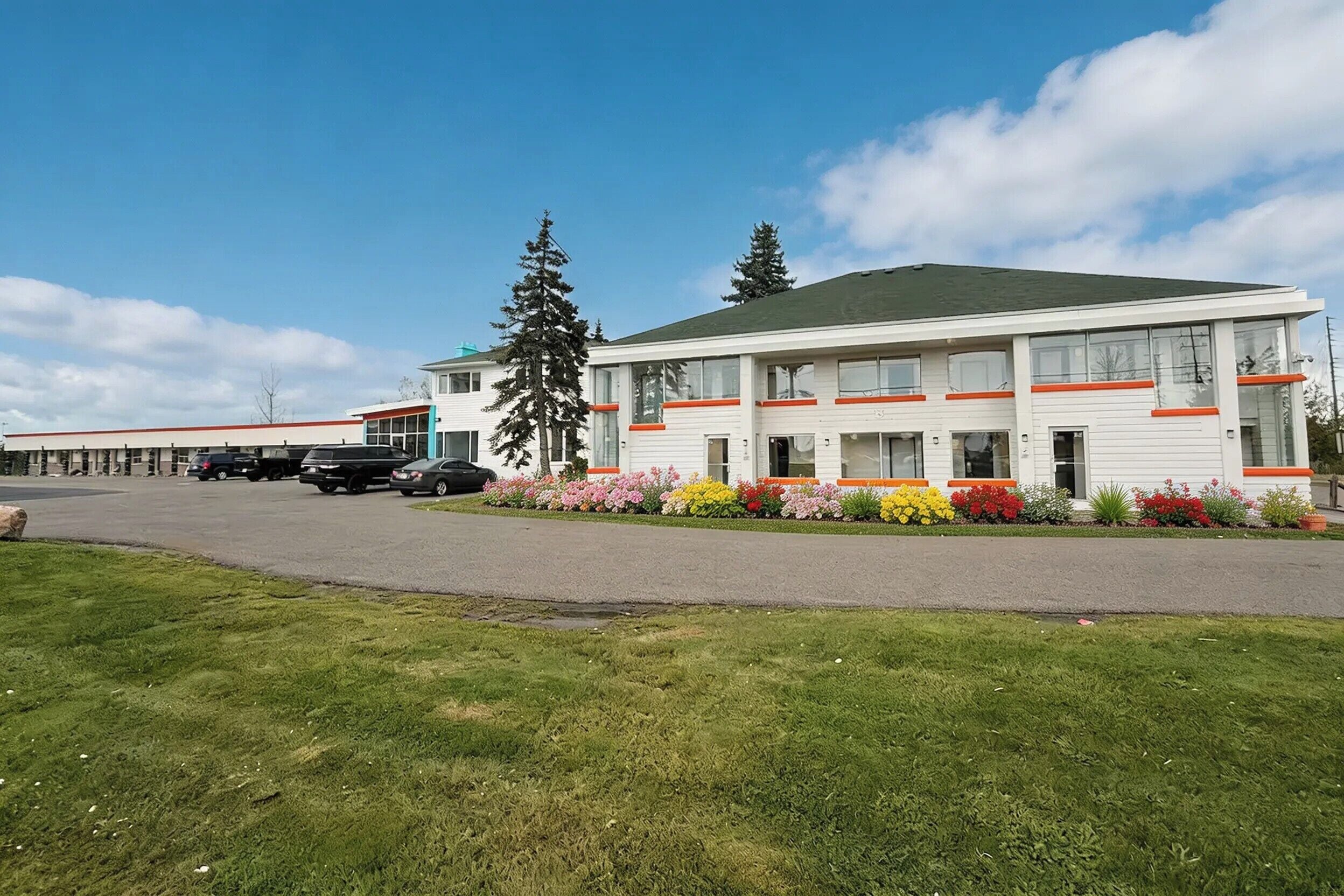 A two-story building with a parking lot and a grassy area in front.