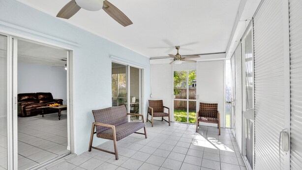 Eine geräumige Terrasse mit Deckenventilator, Schiebetüren und Korbmöbeln.