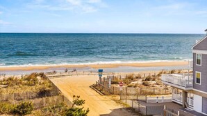 A beach view with a building featuring balconies and a sandy path leading to the water. - Ocean Place 402 | Oceanfront Balcony Views (Ocean City)