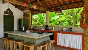 Una cocina con una isla central, taburetes de bar, un refrigerador, un lavamanos y una ventana con vistas a zonas verdes.