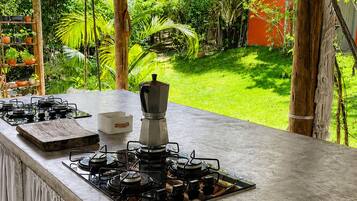 Een keuken met een gasfornuis, een koffiezetapparaat en uitzicht op een weelderige tuin.