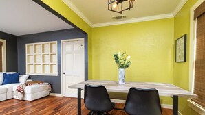 A dining area with a wooden table, two black chairs, a vase with flowers, and a white door. - Fenced Yard, Parking + Workspace - Downtown Dallas (Dallas)