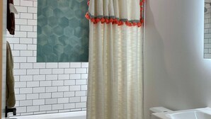 Un baño con una bañera blanca, un inodoro y una ducha.
