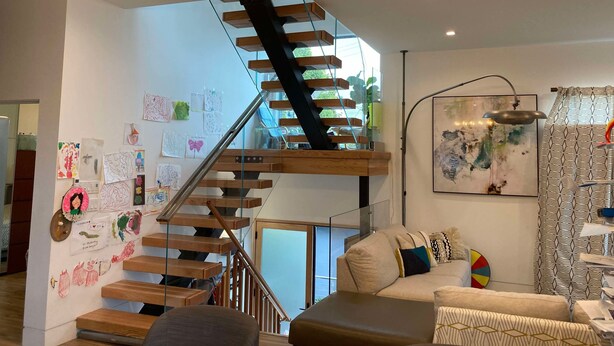 Una sala de estar moderna con escalera de madera, un sofá y una araña.