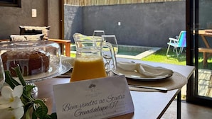 Una preparación para el desayuno que incluye un jarro de vidrio, un pastel cubierto y un menú sobre la mesa.
