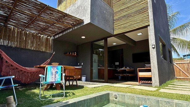 Una casa moderna con piscina, una hamaca y una botella de champán.