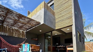 Una casa moderna con piscina, mobiliario exterior y cerca de bambú.