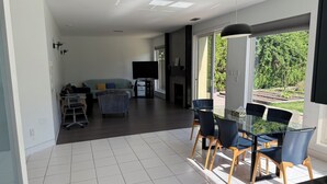 A spacious living area with a dining table and chairs, a sofa, and a television.