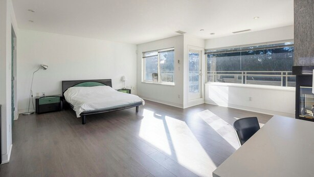 A modern bedroom with a bed, bedside tables, a desk, and a large window.
