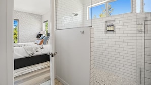 A modern bathroom with white subway tiles, a glass shower enclosure, and a small window. - Luxury Lodge | Hot Tub + Views | 5 Min to DT (Prescott)