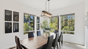 A dining area with a wooden table, black chairs, and a hanging light fixture. - Luxury Lodge | Hot Tub + Views | 5 Min to DT (Prescott)