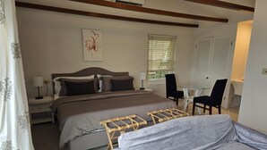 Een slaapkamer met een groot bed, een klein tafeltje en een stoel.