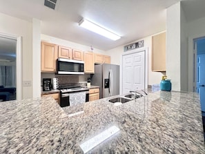 A modern kitchen with granite countertops, stainless steel appliances, and wooden cabinets. - “Quiet Ground‑Floor 2BR/2BA • Pool • No Resort Fees” (Panama City Beach)