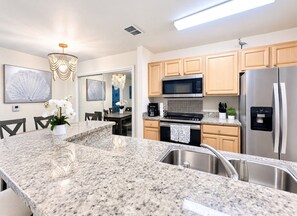 A modern kitchen with granite countertops, stainless steel appliances, and wooden cabinets. - “Quiet Ground‑Floor 2BR/2BA • Pool • No Resort Fees” (Panama City Beach)