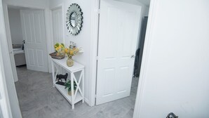 A hallway with white doors, a console table with a vase and flowers, and a decorative mirror.