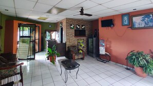 A room with a ceiling fan, a television, a water dispenser, and a potted plant. - Hotel Latino (Santa Ana)