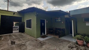 A residential building with a green exterior, a tiled patio, and a brick entrance. - Hotel Latino (Santa Ana)