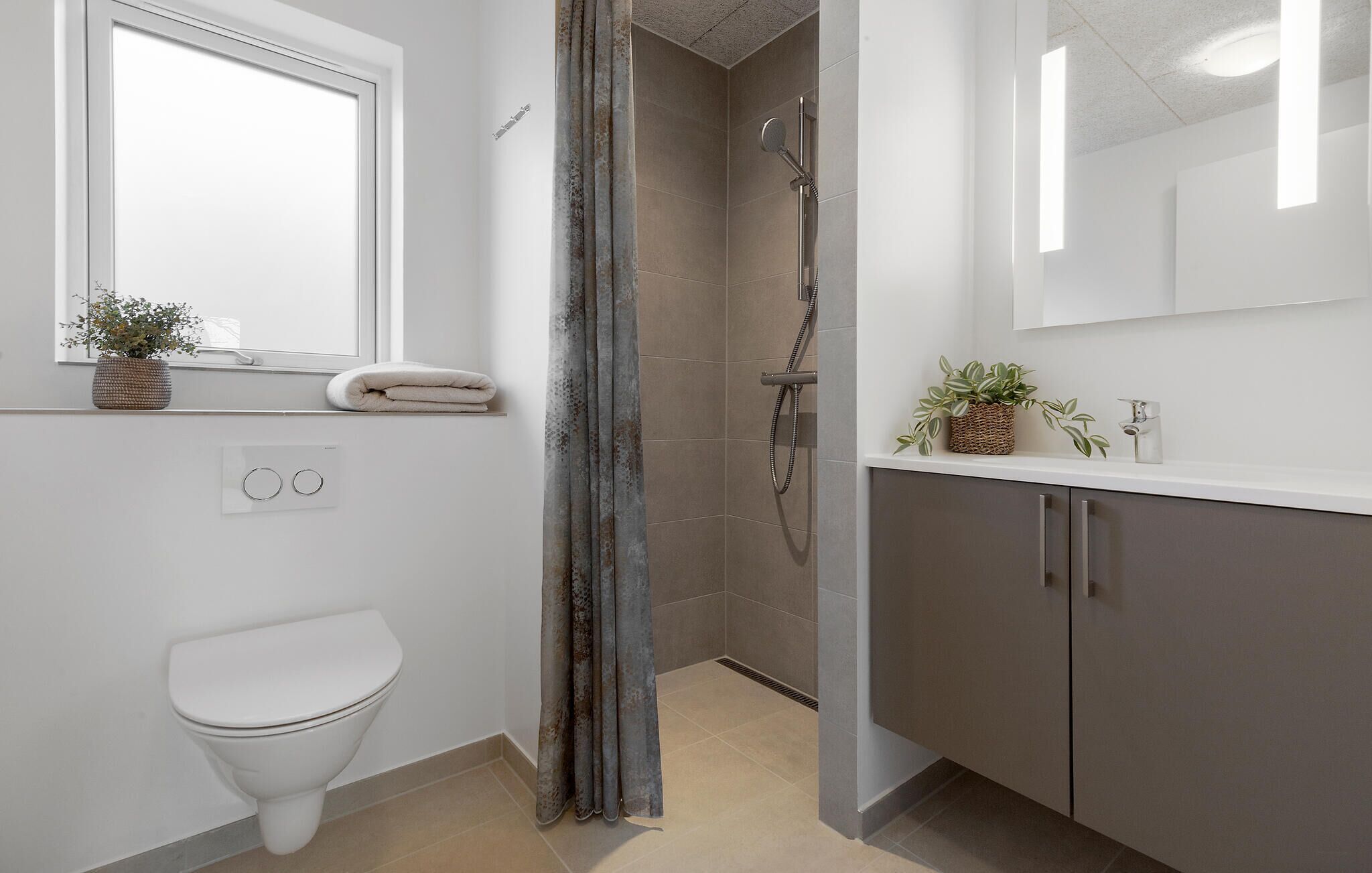 A modern bathroom with a toilet, shower, and vanity.
