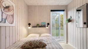 A bedroom with a bed, a pillow, a wall-mounted shelf with a plant, and a painting. - Cozy home in Glesborg with sauna (Glesborg)