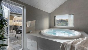 A modern bathroom with a freestanding bathtub, a window, and a view of the outdoors. - Cozy home in Glesborg with sauna (Glesborg)