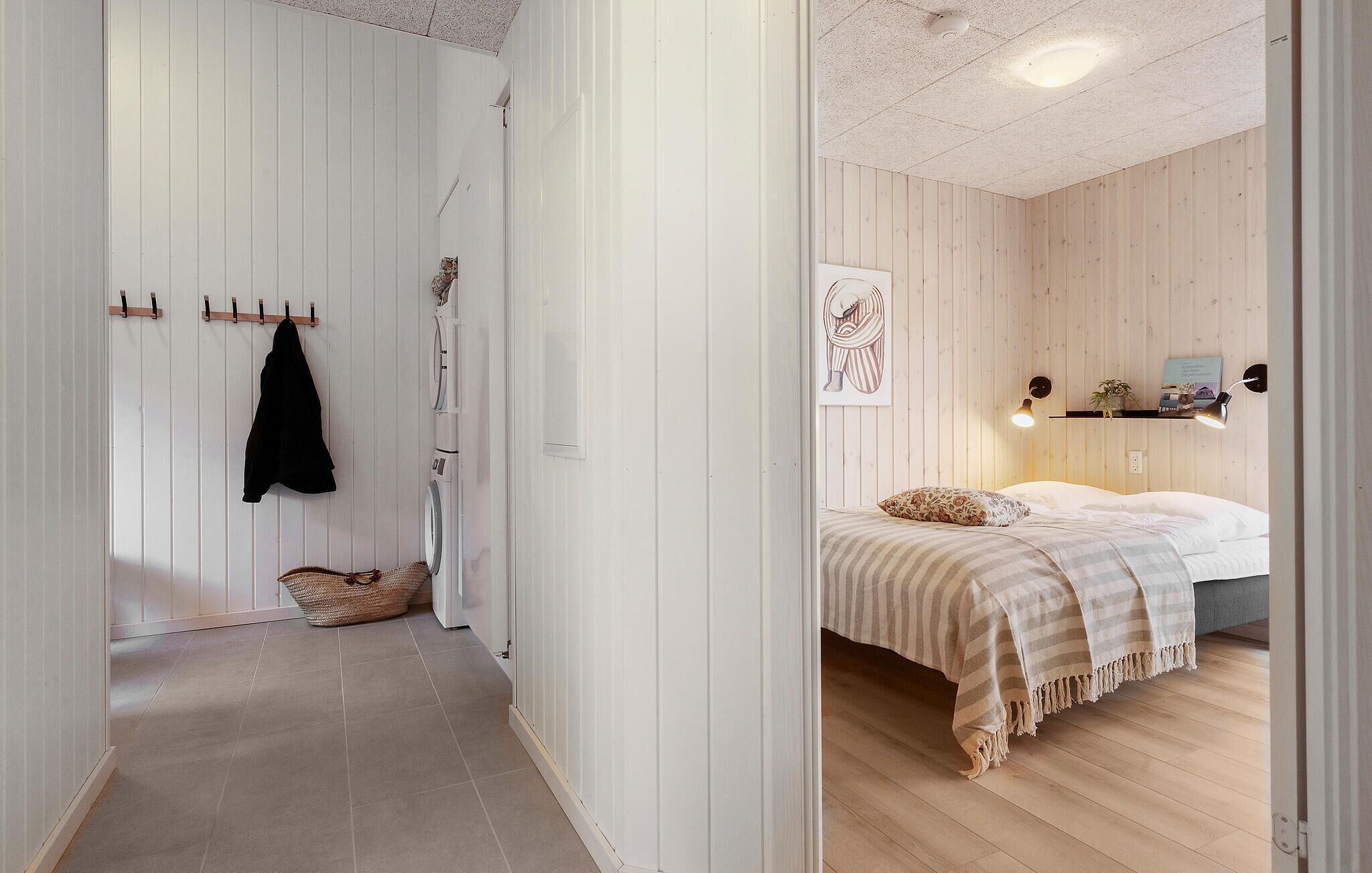 A bedroom with a bed, pillows, a bedside table, and a wall-mounted shelf.