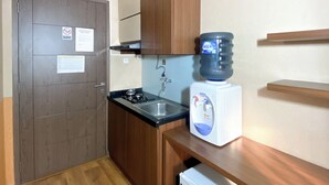 Eine kleine Küche mit Spüle, kleinem Kühlschrank, Wasserspender und Schrank.