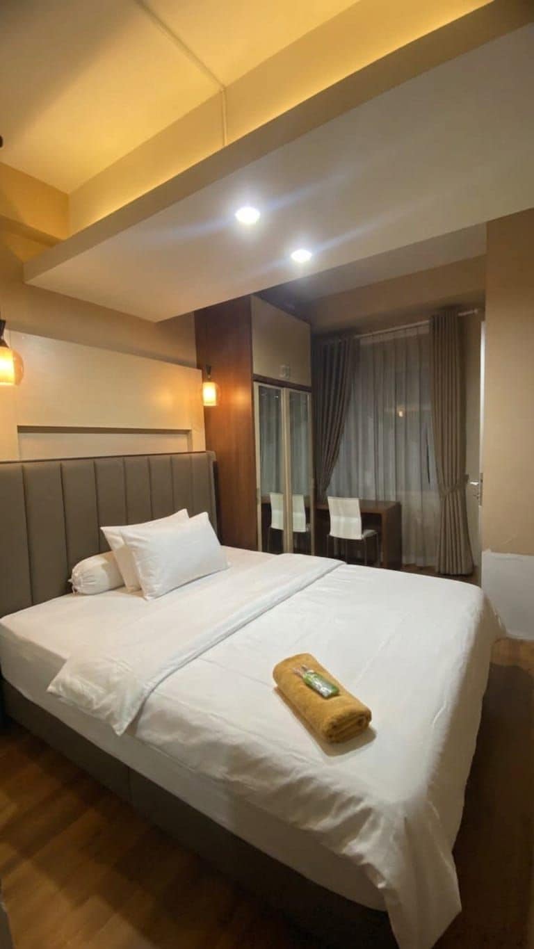 Une chambre d’hôtel avec un grand lit, des tables de chevet, un bureau et une vue sur l’extérieur.